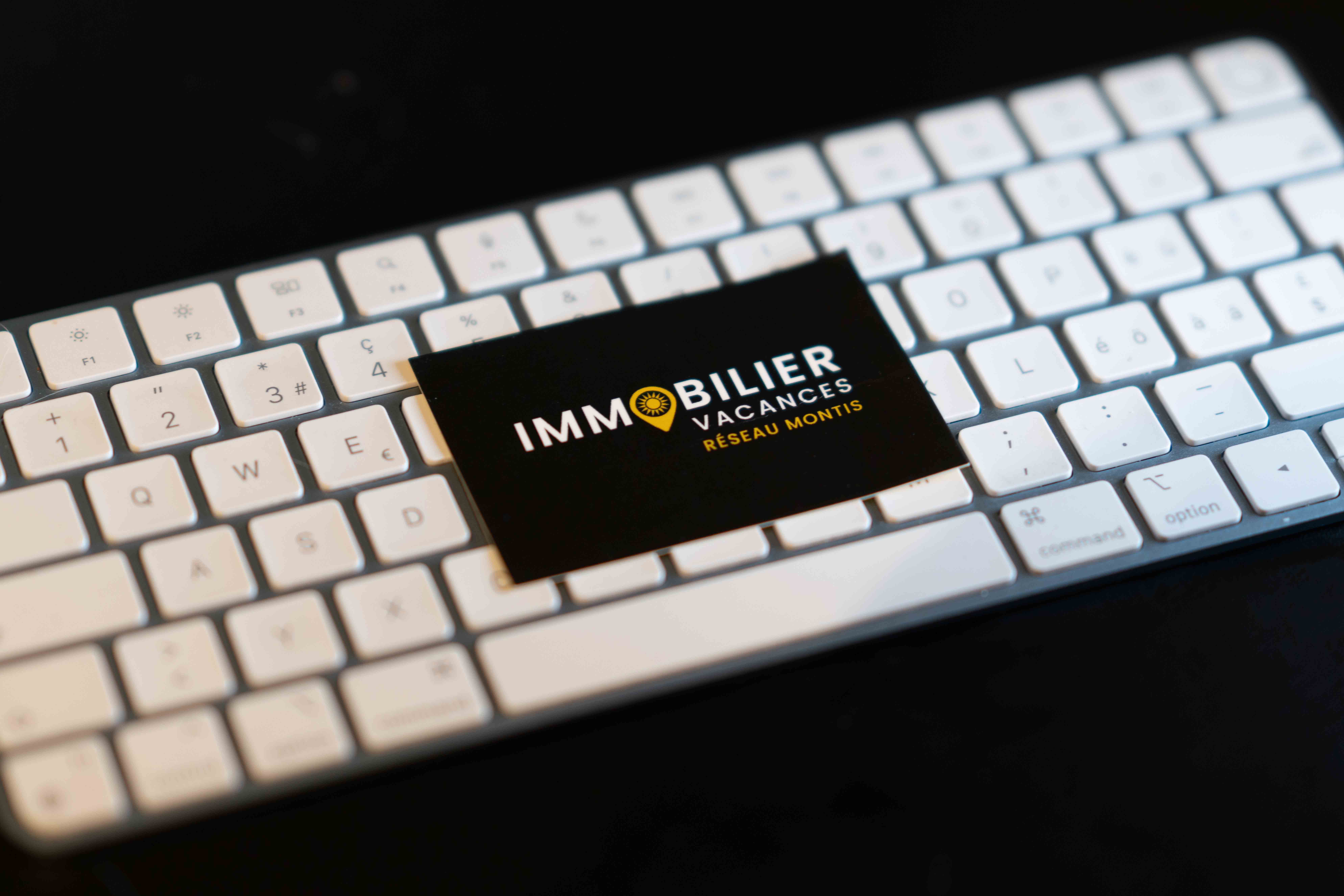 La carte de visite Immobilier Vacances posée sur le clavier de l’agence